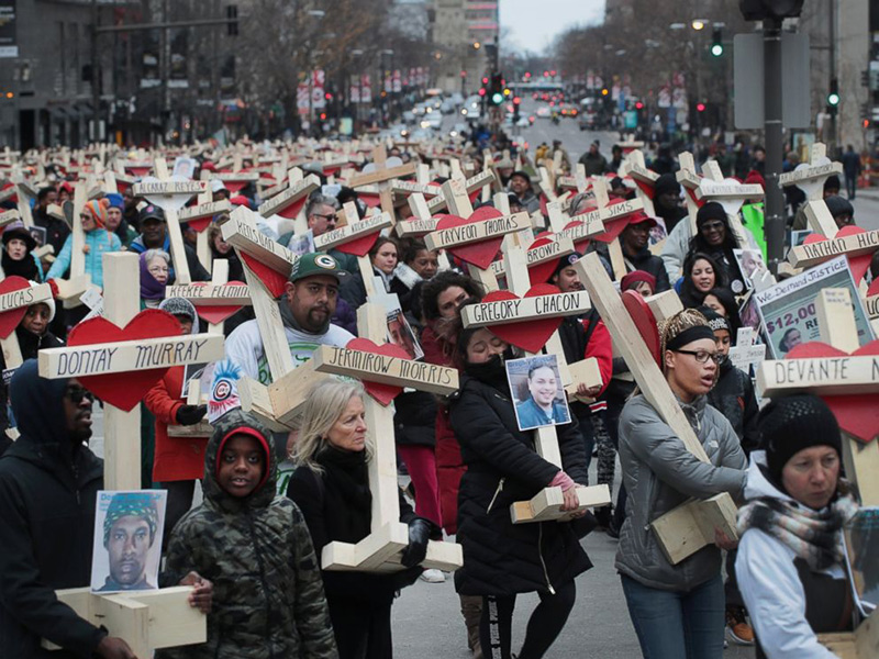 The marchers hold crosses for each kid killed last year.